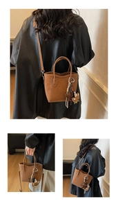 Detailansicht der braunen Retro-Beuteltasche mit Bärenanhänger und Schultergurt