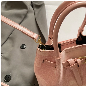 Detail der rosa Jacquard-Beuteltasche mit Stoffstruktur, Ledergriff und Goldbeschlägen