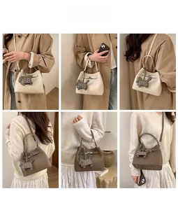 Close-up of pebble leather bucket bag with metal lock and rivet horse charm accessory