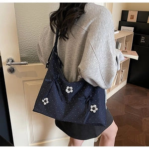 Detail view of navy blue floral tote bag with polka dot pattern and ribbon on a model