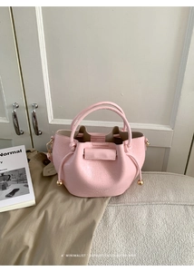 Detail der rosa Kordelzug-Beuteltasche mit glänzender Faltenstruktur und Goldbeschlägen