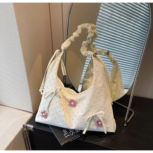 Close-up of white polka dot tote bag with red checkered floral charms and ruffled strap