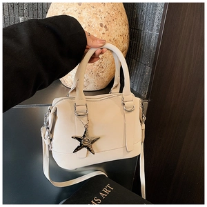 Detail of cream pillow bag featuring a silver star-shaped metallic charm and twin handles