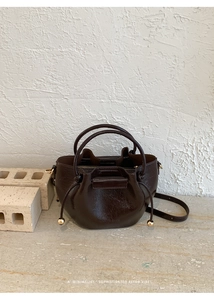 Detail der dunkelbraunen Beuteltasche aus Wachsleder mit Goldperlen und Kordelzugverschluss