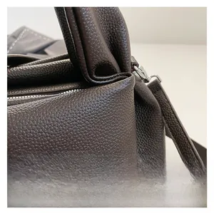 Macro shot of dark brown lychee pattern leather texture and metal hardware on handbag