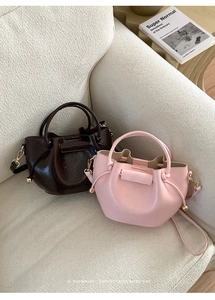 Detail von Kordelzug-Beuteltaschen in Kaffee und Rosa auf einem beigen Sofa