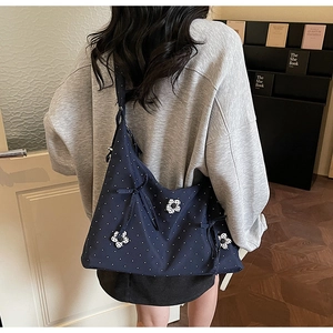 Rear view of a navy blue floral polka dot tote bag worn over the shoulder in a cozy room