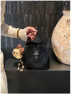 Detail of black matte bucket bag with silver twist lock and a cute plush bear charm