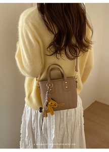 Detailed view of brown textured leather bucket bag with gold rivets and horse charm