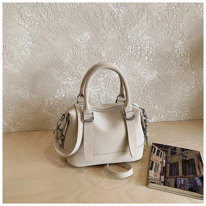 Detail view of beige matte leather bowling bag with silver hardware and adjustable strap