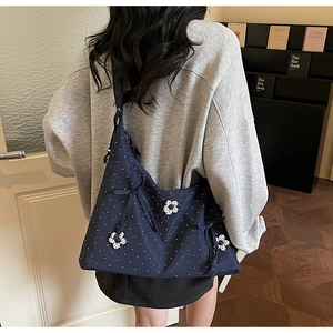 Detail of blue polka dot canvas tote bag with 3D floral accents on model shoulder