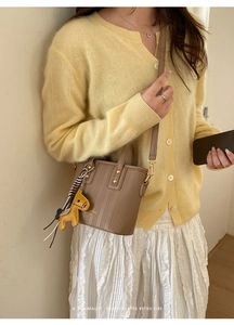 Close-up of brown litchi pattern bucket bag with golden lettering and horse charm detail