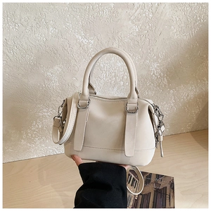 Detail of off-white bowling bag with round handles and silver metal hardware accents