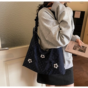 Detail of blue polka dot canvas tote bag featuring floral appliques and ruffled straps