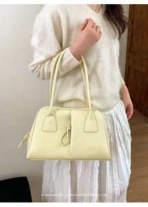 Detail of minimalist cream yellow shoulder bag with elegant knot puller and stitching