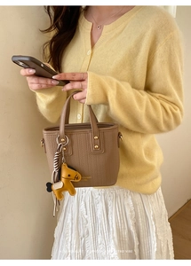 Brown leather bucket bag with woven texture and a yellow horse charm detail