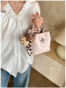 Pink bucket bag with silver twist lock and cute plush puppy charm detail shown held by model