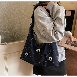 Detail of navy blue polka dot tote bag with 3D floral accents and ruffled shoulder strap