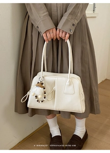 White minimalist PU leather handbag detail with vintage plush doll charm and vertical stitching