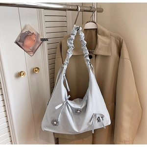 Close-up of light blue polka dot bag with floral charm and ruffled strap on a hanger