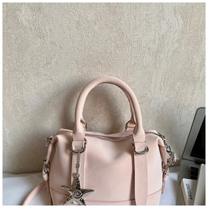 Detail of pink faux leather bag featuring silver star pendant and metallic D-rings