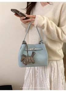 Detail of light blue lychee pattern handbag with silver lock and brown pony charm