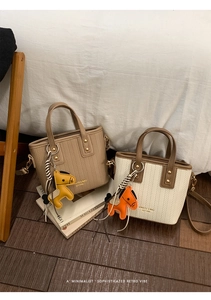 Detail of woven texture tote bags with horse leather charms and brand logo in soft light