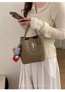 Detail of retro brown bucket bag featuring a metal cross clasp and cute bear charm