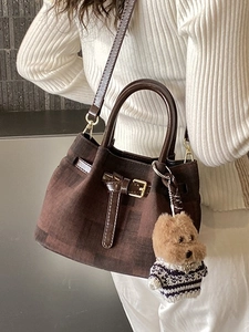 Vintage braune karierte Eimertasche mit Plüschwelpen-Anhänger auf weißem Strickpullover