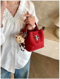 Detail of red suede bucket bag with plush bear charm and decorative beaded chain strap