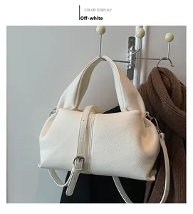 Detail of off-white dumpling bag in lychee leather texture with handle and strap