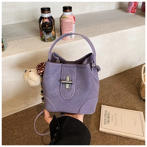 Close-up of purple bucket bag with lychee texture, silver twist lock and plush charm