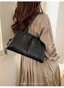 Detail of minimalist black leather tote bag with side drawstring knot and retro vibe