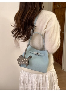 Detail of light blue lychee pattern bucket bag with silver lock and grey horse charm