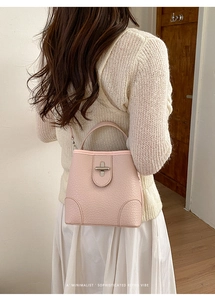 Close-up of light pink bucket bag in lychee pattern leather with a silver swivel lock