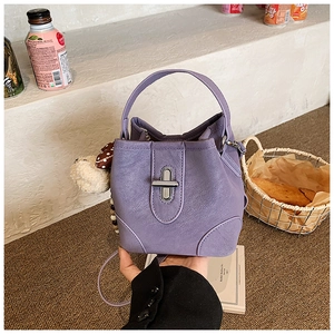 Detail of purple bucket bag with silver twist lock and cute plush bear accessory