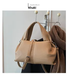 Close-up of khaki dumpling bag in litchi grain leather hanging on a metal hook