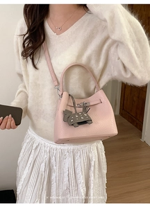 Detail of pink croc-embossed bucket bag with silver twist lock and horse charm