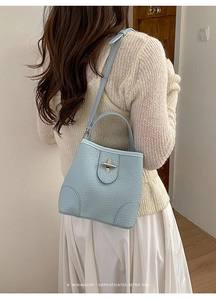 Detail of light blue bucket bag showing pebbled leather texture and silver buckle clasp