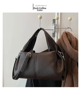 Detail of dark coffee leather handbag featuring pebbled texture and silver buckle