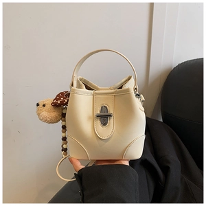 Detail of cream leather bucket bag with silver twist lock and cute plush bear charm