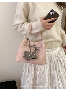 Close-up of minimalist pink bucket bag with leather horse charm and metal turn-lock