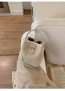 Detailed shot of cream lychee texture bucket bag with silver metal clasp and top handle