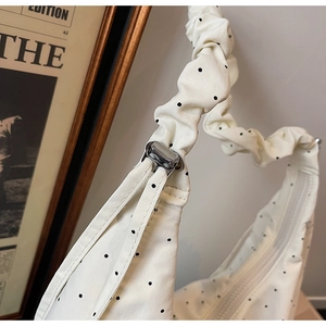 Close-up of ruched shoulder strap and black polka dot pattern on canvas tote bag