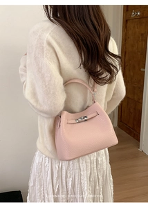 Close-up of pink bucket bag with silver metal lock clasp worn by a female model