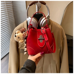 Detail of red bucket bag featuring a silver twist lock and cute bear charm accessory