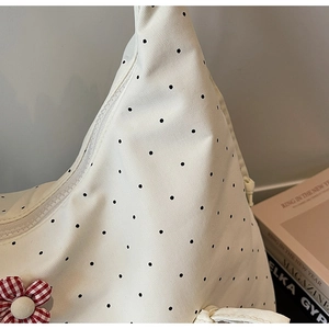 Close-up of white canvas tote bag with black polka dots and red checkered flower detail