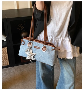 Detail der Vintage-Jeans-Schultertasche mit Lederriemen und silbernem Stern-Anhänger
