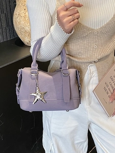 Lavender faux leather bowling bag with star pendant shown on a model's arm