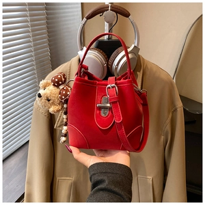 Macro detail of red matte bucket bag with silver clasp and plush bear charm